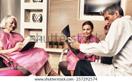 Male doctor showing x-ray exam to woman patient, with patient mother reading a book.