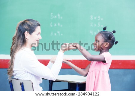Happy teacher and afroamerican elementary student congratulating during math lesson.