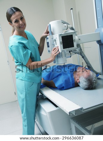 Smiling female doctor scanning male patient with x-ray machine.