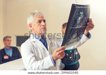 Expert doctor analyzing x-ray scan at hospital.