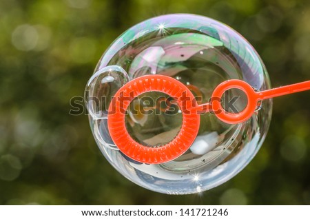 Close up of a soap bubble growing from the blower ring