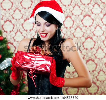 Beautiful girl in santa hat near a christmas tree with gifts