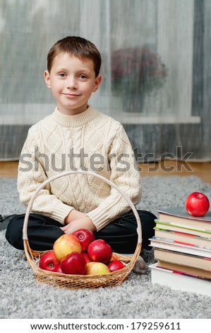 boy with apples and books  at home on the carpet
