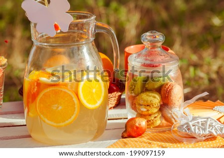 Decorated picnic with oranges and lemonade in the summer garden