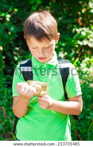boy with a backpack and a clock in hands on nature