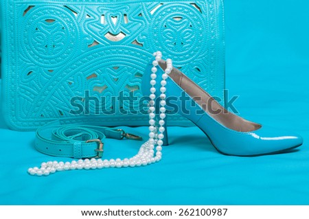 Beautiful blue shoes and handbag, pearls on blue background