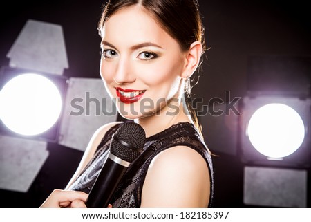 Close-up portrait of beautiful elegant young woman with microphone