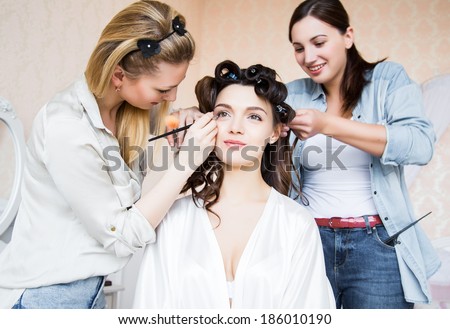 Stylist and makeup artist preparing bride before the wedding in a morning