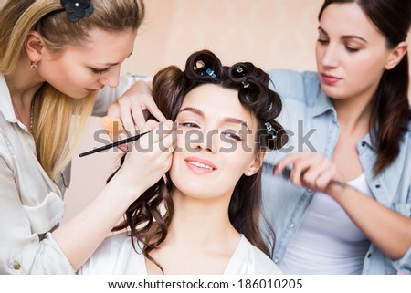 Stylist and makeup artist preparing bride before the wedding in a morning