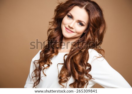 Close-up portrait of beautiful sexy young woman with long brown hair over brown background