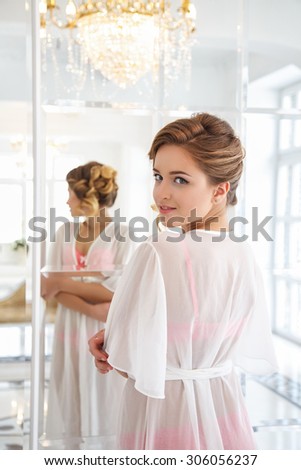Beautiful bride in white lingerie looking at mirror in a morning