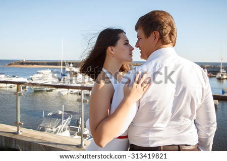 Beautiful couple man and woman walks together near yacht in a summer day