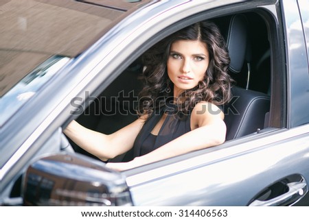 Close-up portrait of gorgeous young brunette woman driving an expensive car