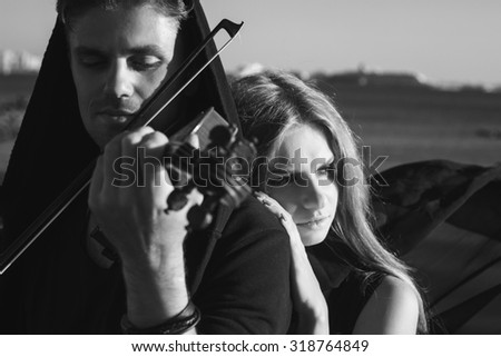 Beautiful couple violinist and young woman together near sea bay. black and white