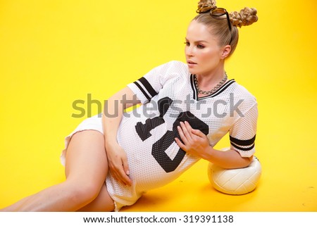 Beautiful pregnant woman in sport style - isolated over a yellow background