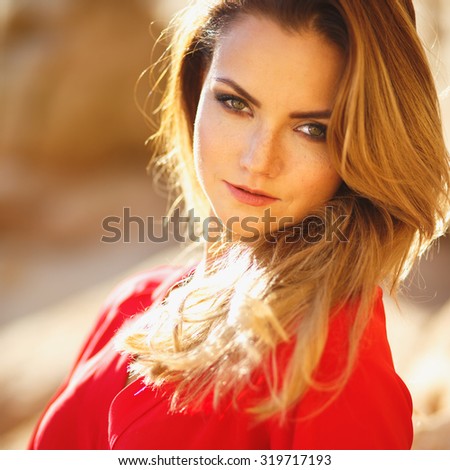 Gorgeous red head young woman in long red dress in a dessert. Sandy canyon. Fashion style