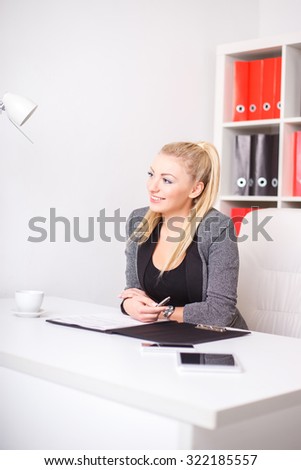beautiful modern businesswoman in her office with a paper folder and tablet computer and mobile phone