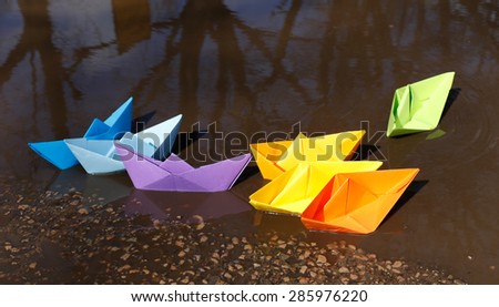 Colorful rainbow paper boats floating in pond