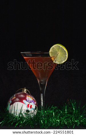 The photograph shows a chilled cocktail glass with a cocktail and christmas decorations.