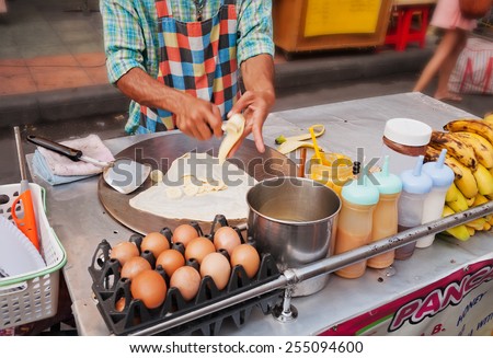 BANGKOK, THAILAND - DEC 7, 2013 : Man cooks Thai Banana Pancake on the street  Khaosan Road. Khaosan Road or Khao Sarn Road  is a short tourist walking street in central Bangkok