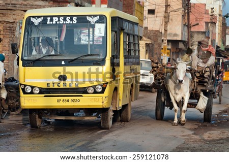 VRINDAVAN, INDIA - DEC 15, 2014:  Bullock cart and bus on the road. Vrindavan is considered to be a holy place. The major tradition followed in the area is Vaisnavism