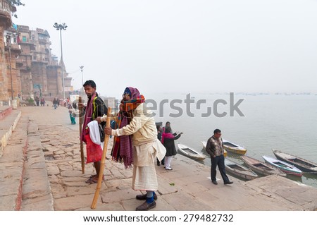 VARANASI, INDIA - DEC 23, 2014: Unidentified Indian old man with his son go on steps of Ghats in Varanasi. Uttar Pradesh, India