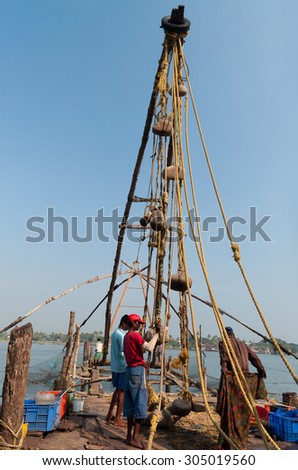 Fort Kochi, India - Jan 6, 2015: Unidentified Indian fishermen descend their Chinese fishing net into the sea  in the beach of Fort Kochi. Kerala