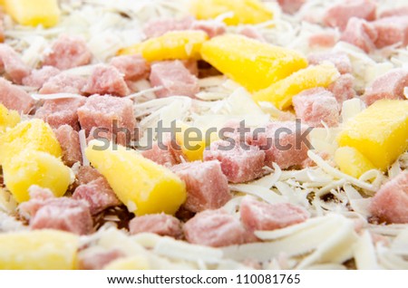 Closeup of a frozen hawaiian pizza with pineapple and ham.
