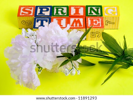 A fake spring flower below some baby blocks that spell spring time