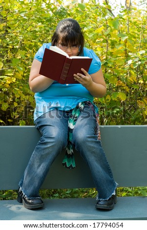 A young girl reading a book outside