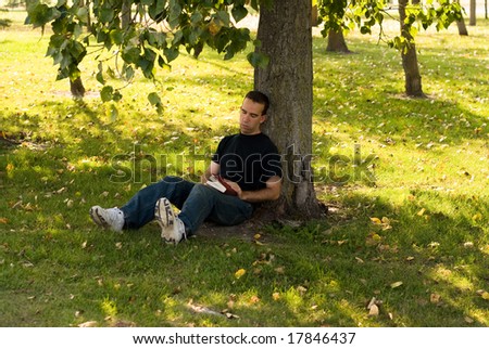 A young man resting under a shady tree