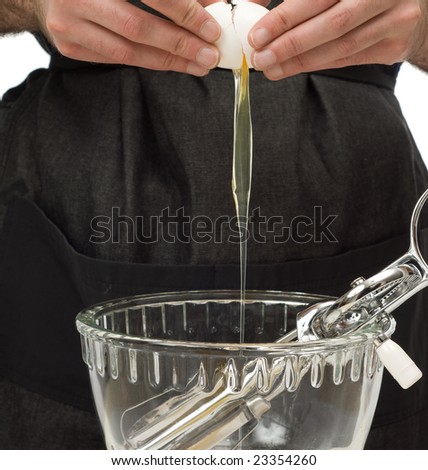 A young man preparing an egg to be mixed into some batter