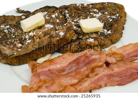 Closeup of some French Toast and bacon, shot on a white plate