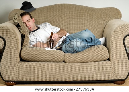 A young man sleeping on the couch with a bottle of beer