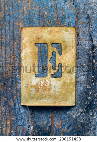 Metal typography over a weathered wood background showing the alphabet letter \
