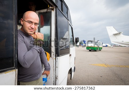 Bald man waiting for flight in airport bus door.
