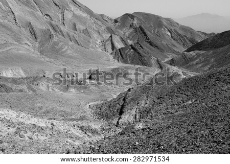 Black and white desert rocks mountains cliffs texture, canyons gorges dry riverbeds, Eilat area, Negev desert, Israel.