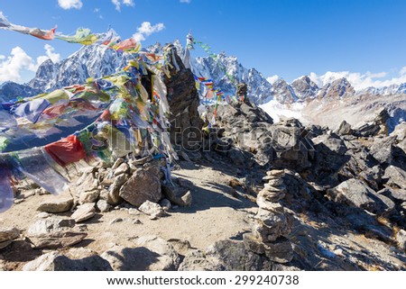 Buddhist prayer flags stones, Gokyo Ri mountain summit peak ascent, snow mountains peaks. Everest Base Camp trail route, trekking Nepal culture, Himalaya ridge traveling.