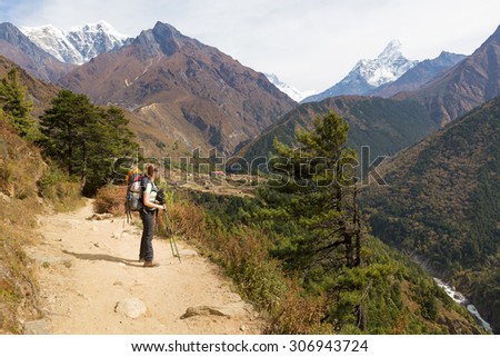 Young woman backpacker tourist standing looking Ama Dablam mountain snow peaks above deep canyon river. Everest Base Camp trekking route trail, Nepal traveling tourism.