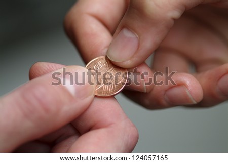Hand giving 2 cents euro coin to other hand.Shallow focus.