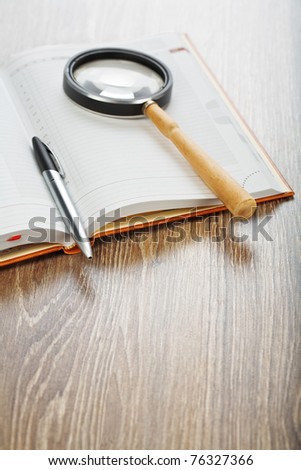 pen and magnifying glass on notebook