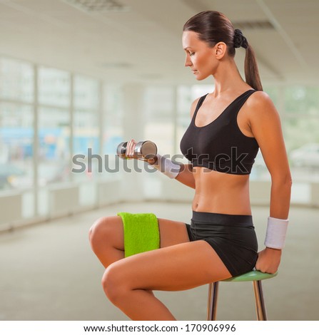 beautiful female lifting weight and sitting on chair