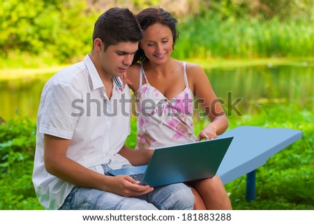 youg couple loking in laptop on nature