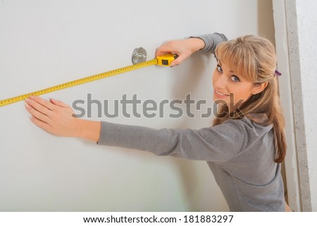 female worker measuring white wall