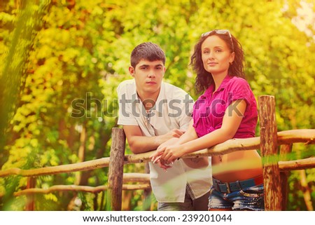 young couple standing on old wooden bridge and looking at camera instagram stile