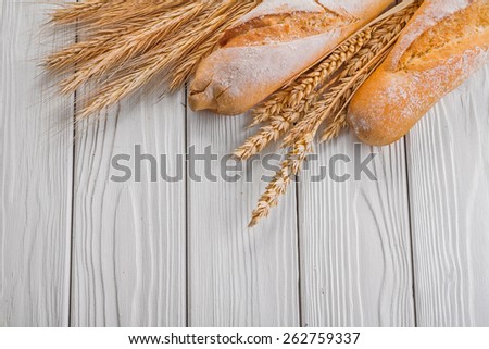 baguettes and ears of wheat rye on vintage wooden painted boards food and drink concept
