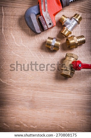 monkey wrench and brass plumbing fixtures  on wooden board with organized copyspace construction concept