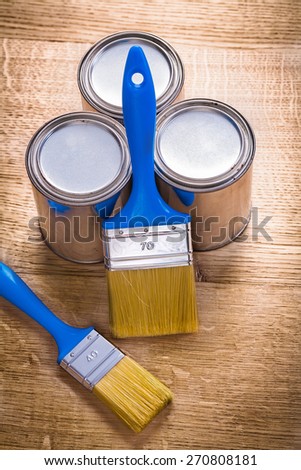 two paint brushes and three cans on wooden board construction concept