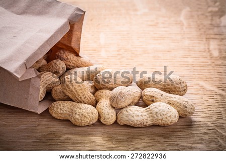 peanuts and paper bag on wooden board food and drink concept