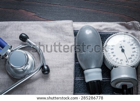 Medical stethoscope and tonometer with pressure band on vintage wooden background medicine concept